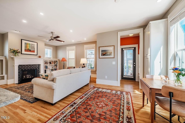 living room with light wood-style flooring, recessed lighting, a fireplace, a ceiling fan, and baseboards