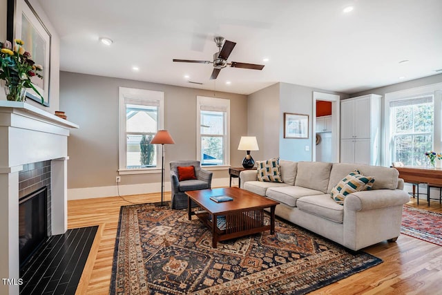 living area featuring ceiling fan, recessed lighting, a fireplace with flush hearth, baseboards, and light wood-type flooring