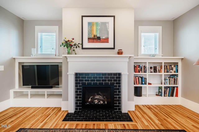 unfurnished living room featuring a fireplace, baseboards, and wood finished floors