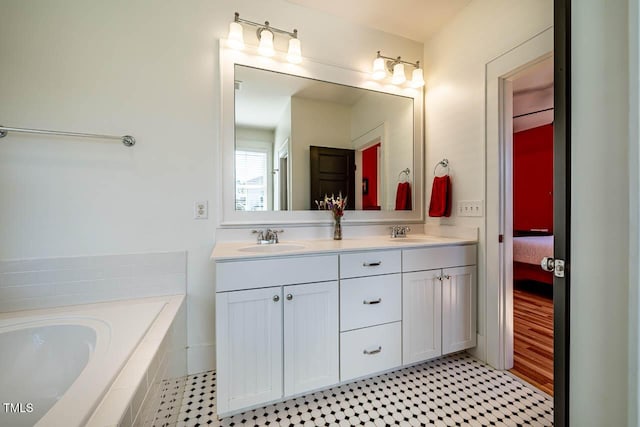 bathroom with tiled bath, a sink, and double vanity