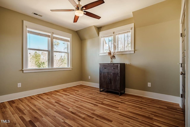 spare room with a healthy amount of sunlight, visible vents, baseboards, and wood finished floors