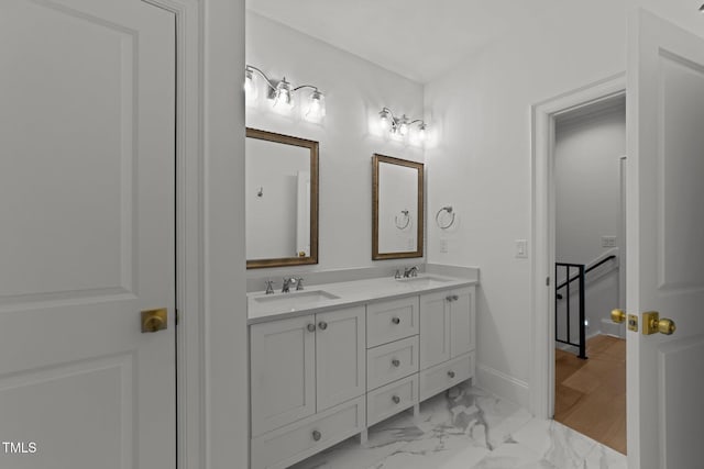 bathroom featuring double vanity, marble finish floor, baseboards, and a sink