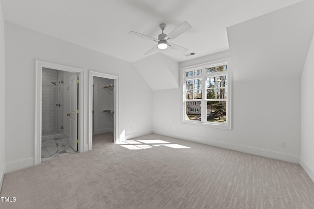 unfurnished bedroom featuring ensuite bathroom, carpet floors, baseboards, vaulted ceiling, and a spacious closet