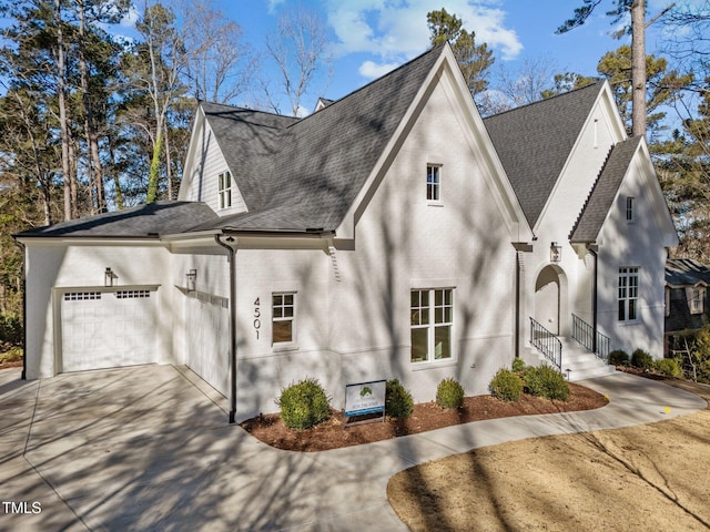 view of front of property featuring a garage, a shingled roof, concrete driveway, and brick siding