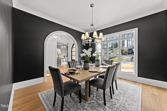 dining area with arched walkways, a healthy amount of sunlight, baseboards, and a notable chandelier