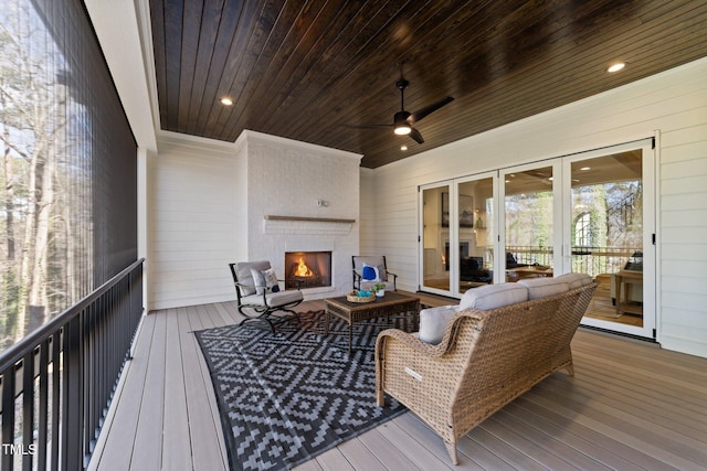 sunroom featuring ceiling fan, a fireplace, and wood ceiling