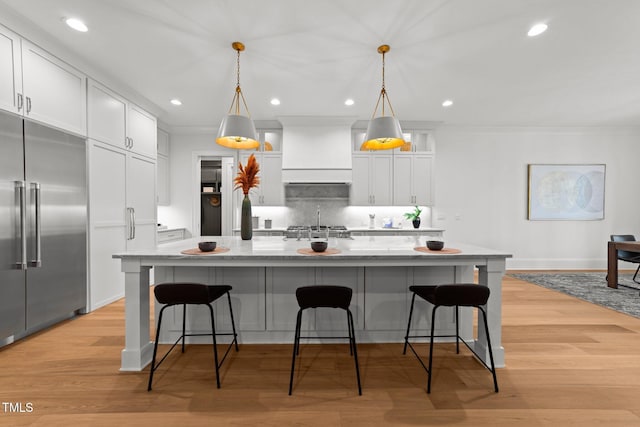 kitchen featuring stainless steel appliances, white cabinets, light wood finished floors, and decorative backsplash