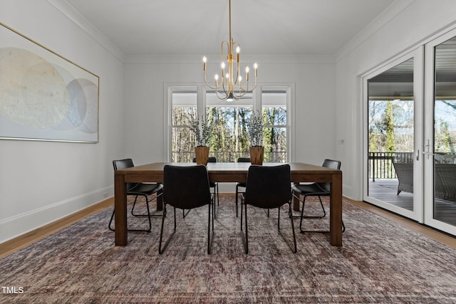 dining space with ornamental molding, a chandelier, plenty of natural light, and wood finished floors