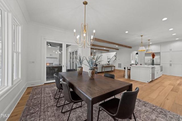 dining room with light wood-style floors, arched walkways, and plenty of natural light