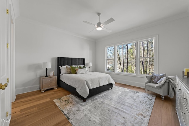 bedroom featuring light wood finished floors, ornamental molding, and baseboards