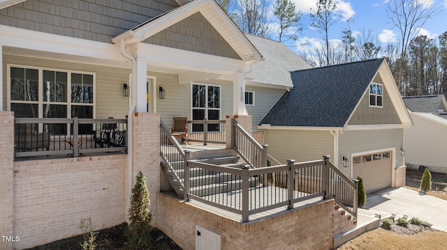 view of front of house with a shingled roof, covered porch, concrete driveway, stairway, and a garage