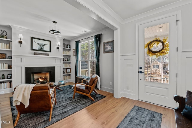 112 Rawhide Dr, Louisburg, NC 27549 - living room with a lit fireplace, crown molding, light wood-style flooring, built in features, and baseboards