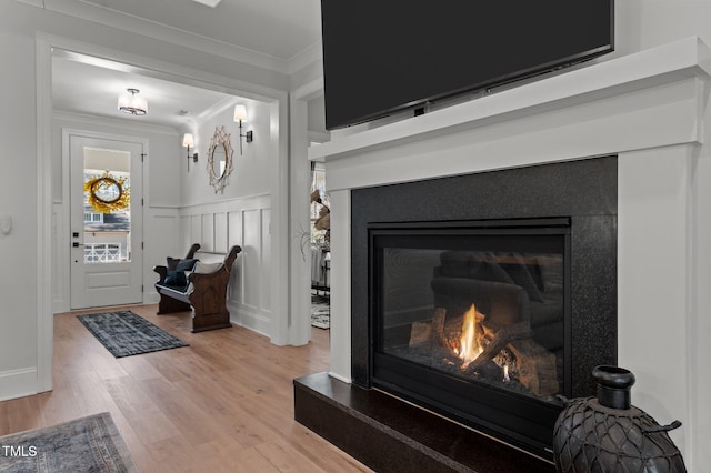 112 Rawhide Dr, Louisburg, NC 27549 - interior details featuring a wainscoted wall, a decorative wall, ornamental molding, wood finished floors, and a glass covered fireplace