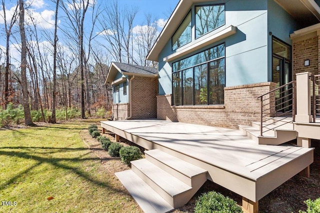 view of side of property featuring stucco siding, brick siding, and a lawn