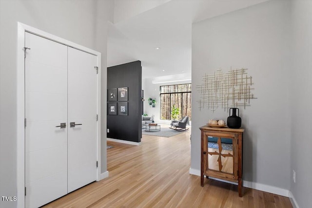 hall featuring light wood-style flooring and baseboards