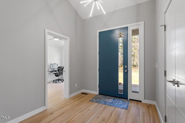 foyer with lofted ceiling, wood finished floors, baseboards, and visible vents