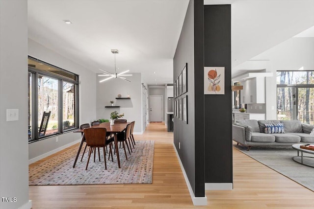 dining area with a notable chandelier, baseboards, and light wood-type flooring