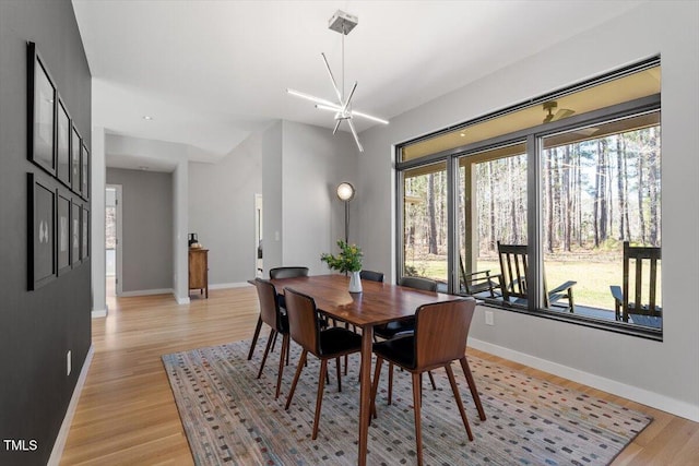 dining space featuring light wood finished floors, an inviting chandelier, and baseboards