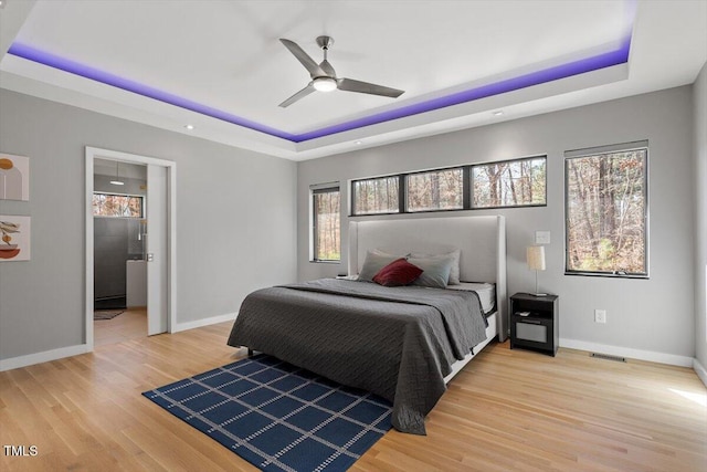 bedroom featuring a raised ceiling, visible vents, and light wood-type flooring