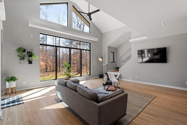 living area featuring recessed lighting, a high ceiling, baseboards, and wood finished floors