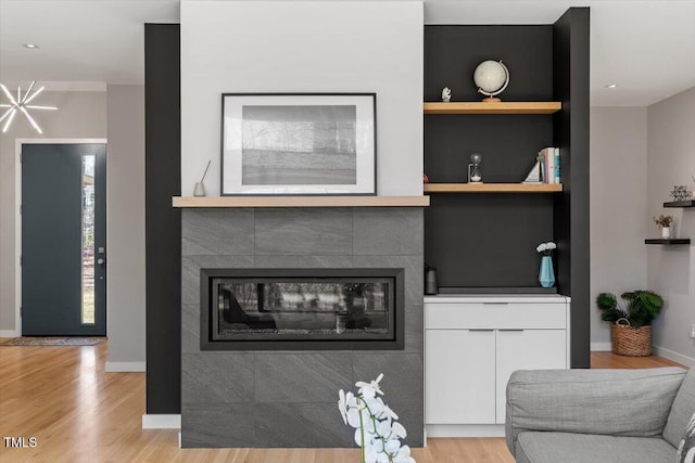 living area with light wood-style flooring, built in shelves, a fireplace, and baseboards