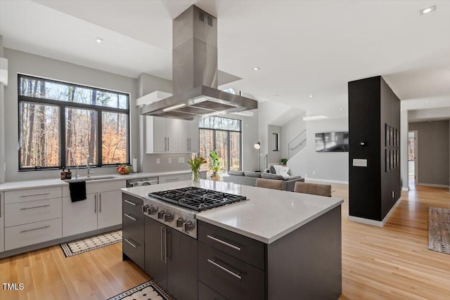 kitchen featuring light wood-style flooring, island exhaust hood, a wealth of natural light, and stainless steel gas cooktop