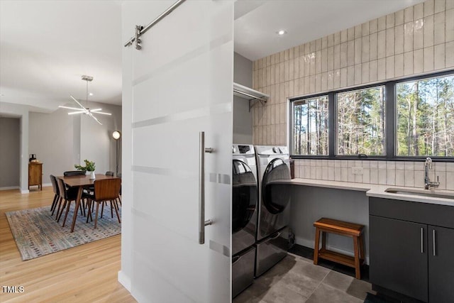 laundry area featuring light wood-style flooring, a ceiling fan, a sink, washing machine and dryer, and laundry area