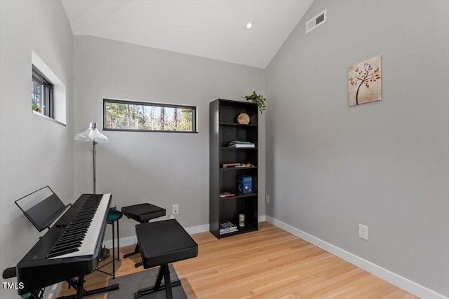 office space featuring visible vents, baseboards, light wood-style flooring, and vaulted ceiling