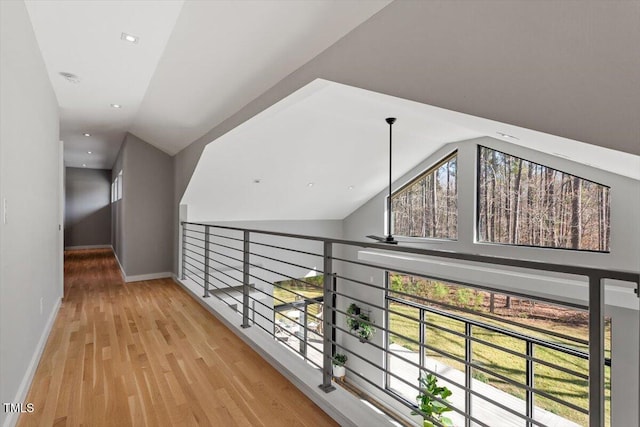 hallway featuring a wealth of natural light, lofted ceiling, baseboards, and wood finished floors