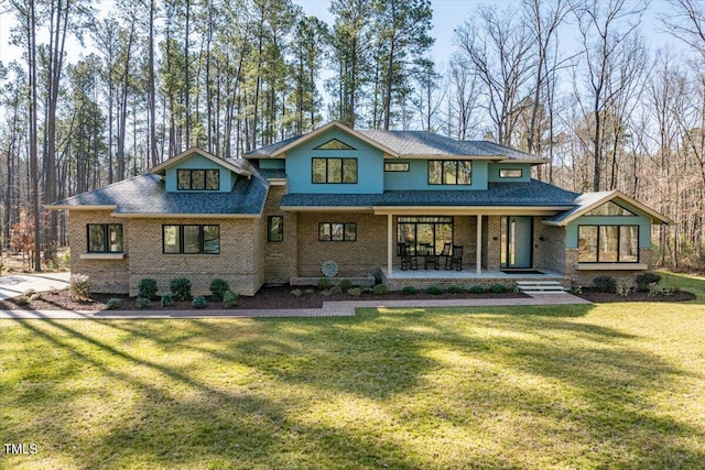 view of front of property featuring a front yard, brick siding, and covered porch