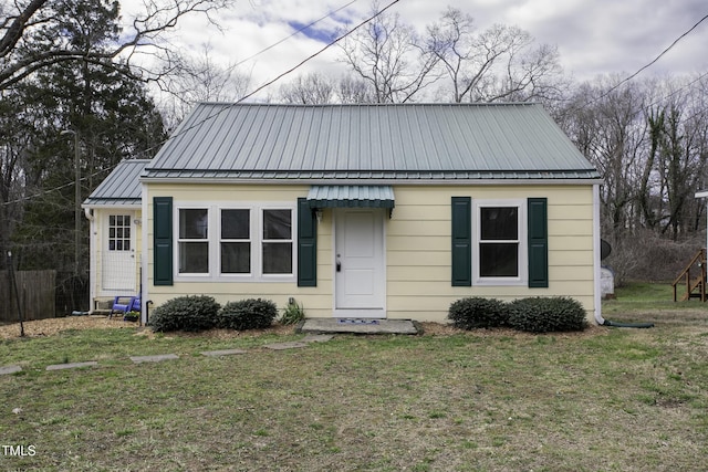 bungalow-style house featuring a front yard, a standing seam roof, metal roof, and fence