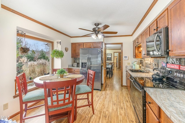 kitchen with brown cabinets, appliances with stainless steel finishes, a ceiling fan, and a sink