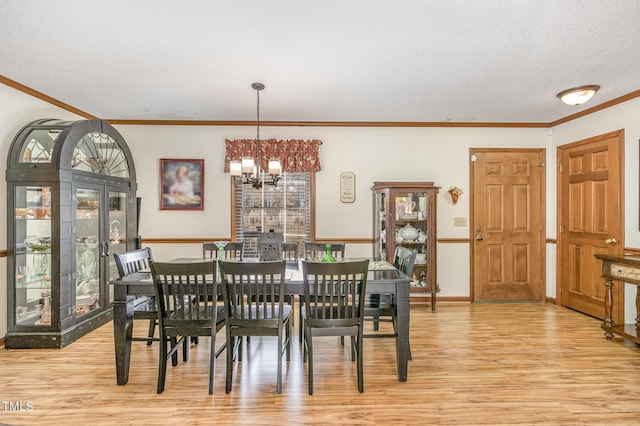 dining room with light wood-type flooring, baseboards, an inviting chandelier, and crown molding
