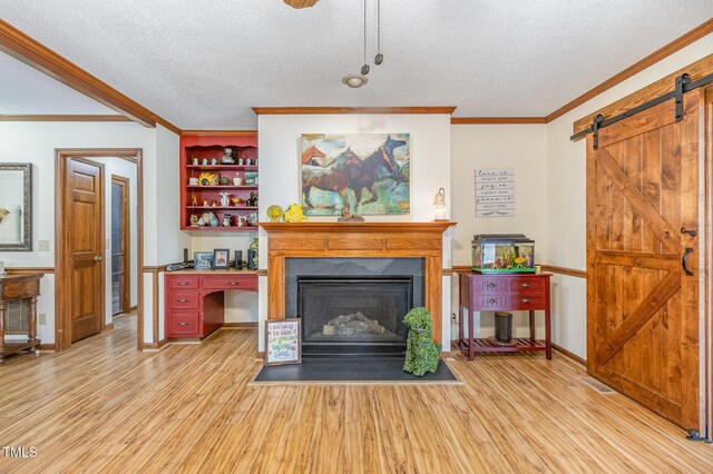 living room featuring a barn door, light wood-style floors, and ornamental molding