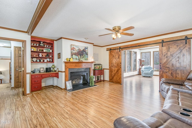 living room with a barn door, light wood-style flooring, and crown molding
