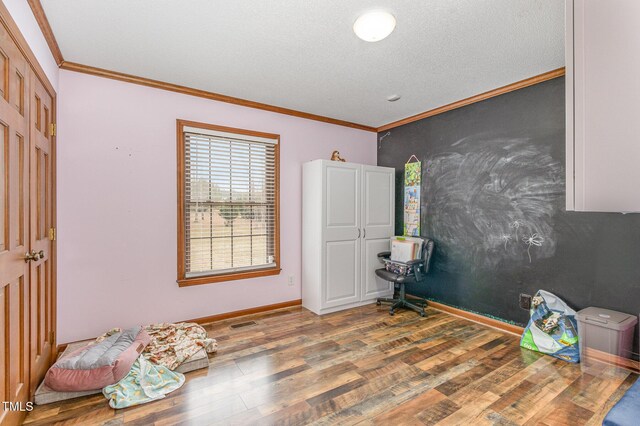 bedroom with baseboards, a textured ceiling, wood finished floors, and crown molding