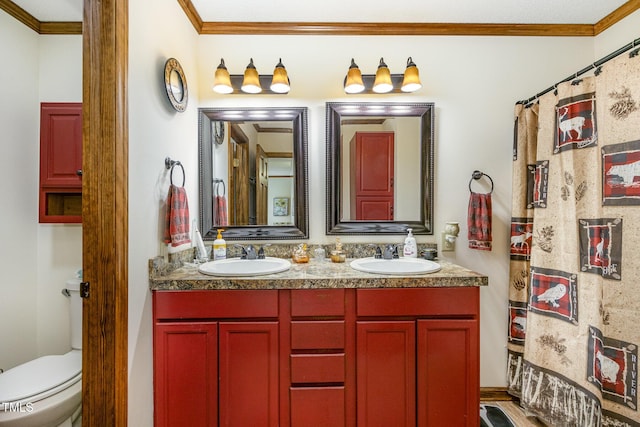 full bath with a sink, toilet, double vanity, and crown molding