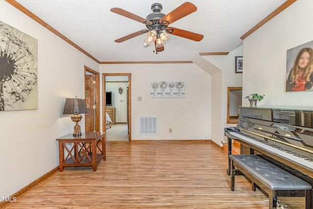 interior space featuring a ceiling fan, visible vents, light wood finished floors, and ornamental molding