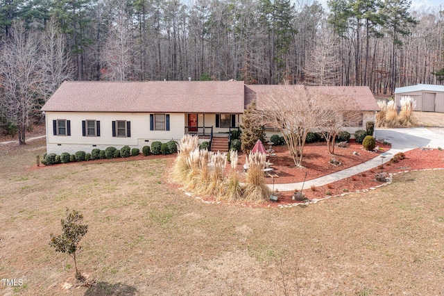 ranch-style house with driveway, a view of trees, and a front lawn