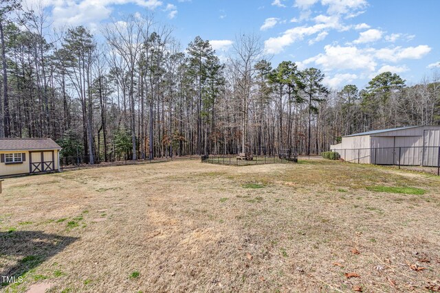 view of yard with an outbuilding, fence, and a forest view