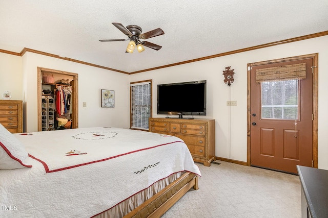 bedroom featuring a walk in closet, a textured ceiling, crown molding, baseboards, and ceiling fan