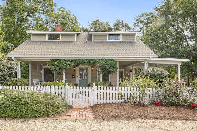 view of front of house featuring a fenced front yard, a chimney, a porch, and a shingled roof