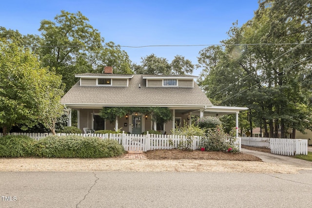 view of front of property with covered porch, roof with shingles, and a fenced front yard