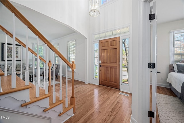 foyer with stairs, wood finished floors, arched walkways, and baseboards