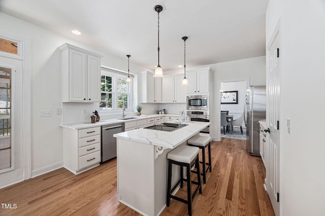 kitchen featuring light wood-style flooring, a kitchen breakfast bar, tasteful backsplash, white cabinetry, and stainless steel appliances