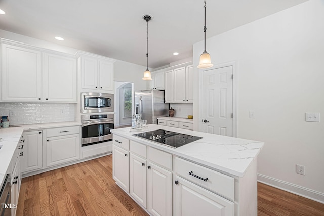 kitchen featuring backsplash, light wood-style flooring, appliances with stainless steel finishes, and a center island