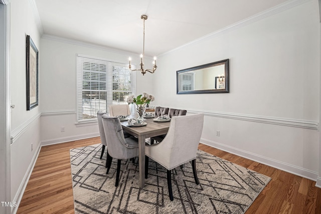 dining space featuring light wood-style floors, baseboards, a chandelier, and ornamental molding