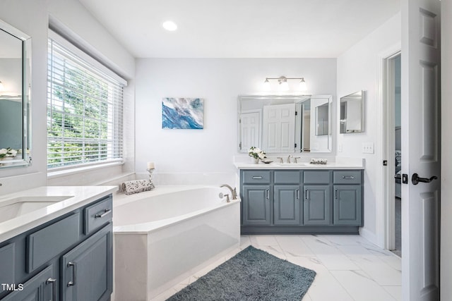 bathroom with a sink, two vanities, marble finish floor, and a bath