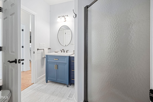 bathroom with vanity, wood finished floors, a shower stall, and toilet