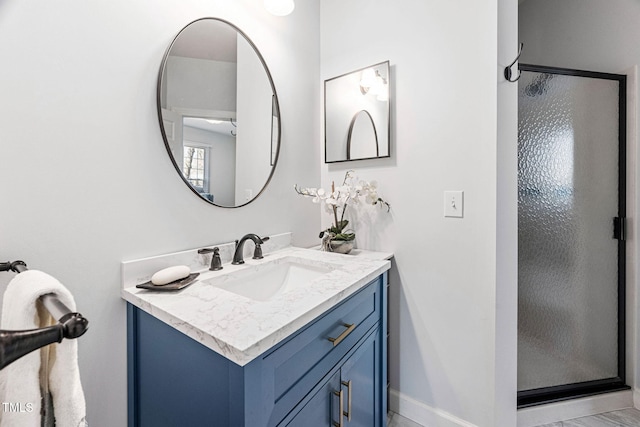 bathroom with baseboards, a stall shower, and vanity